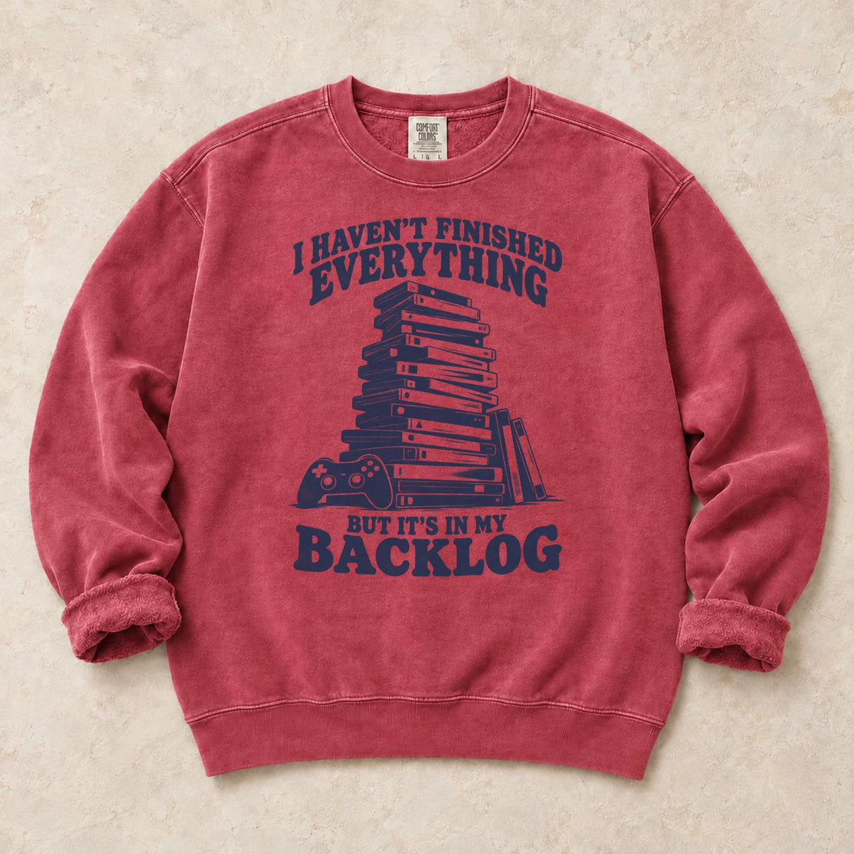 Crimson gaming sweatshirt. A game stack admits everything unfinished is in the backlog.