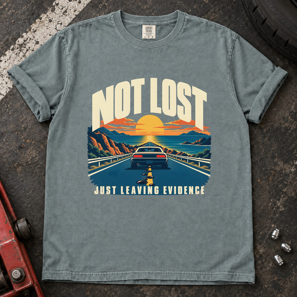 Bay T-shirt showing a car on a sunset road with 'Not lost. Just leaving evidence'.