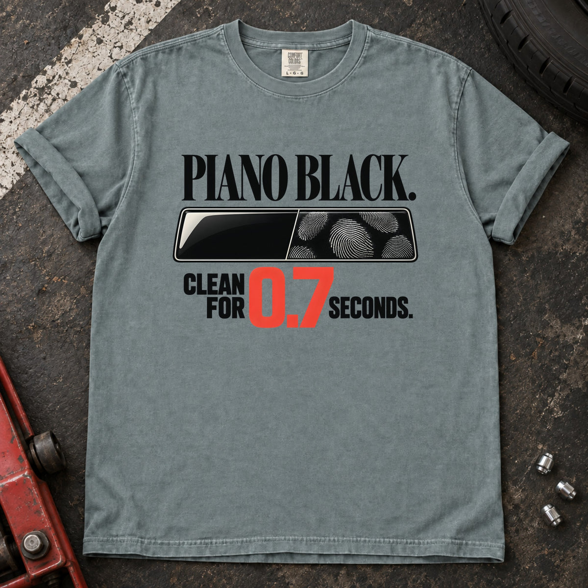 Bay T-shirt showing fingerprints on a trim panel with 'Piano black. Clean for 0.7 seconds'.