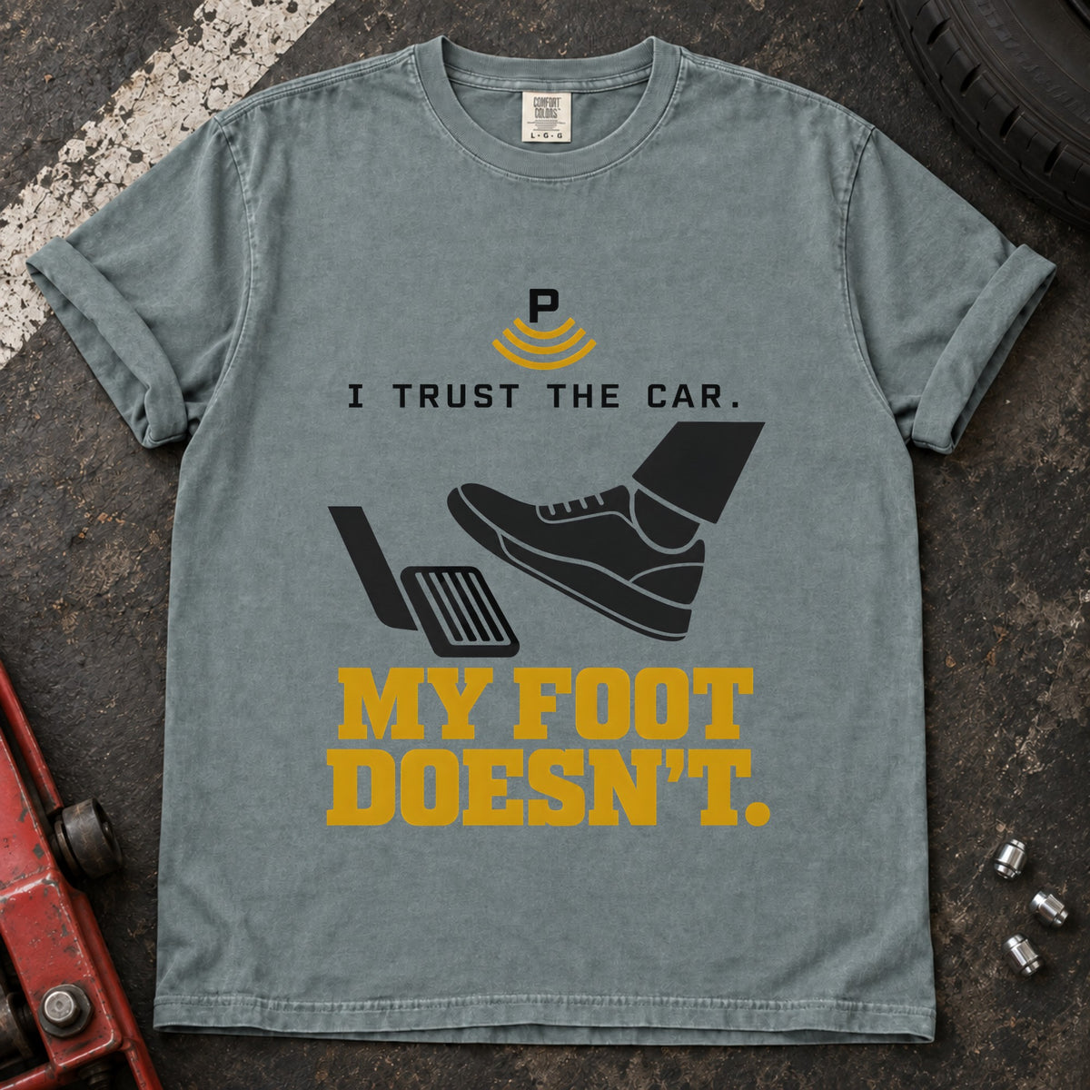 Bay T-shirt showing a shoe near a pedal and a parking-assist symbol with 'I trust the car. My foot doesn't'.