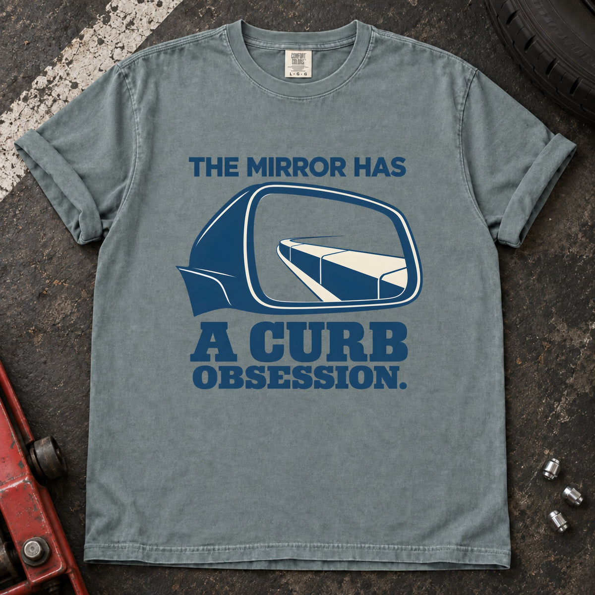 Bay T-shirt showing a side mirror reflecting a curb with 'The mirror has a curb obsession'.
