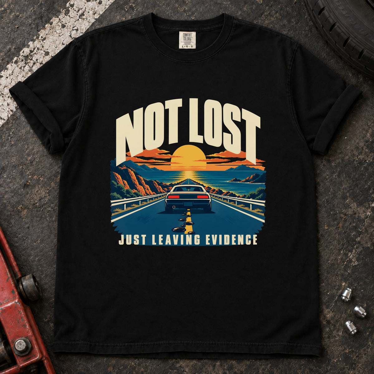 Black T-shirt showing a car on a sunset road with 'Not lost. Just leaving evidence'.