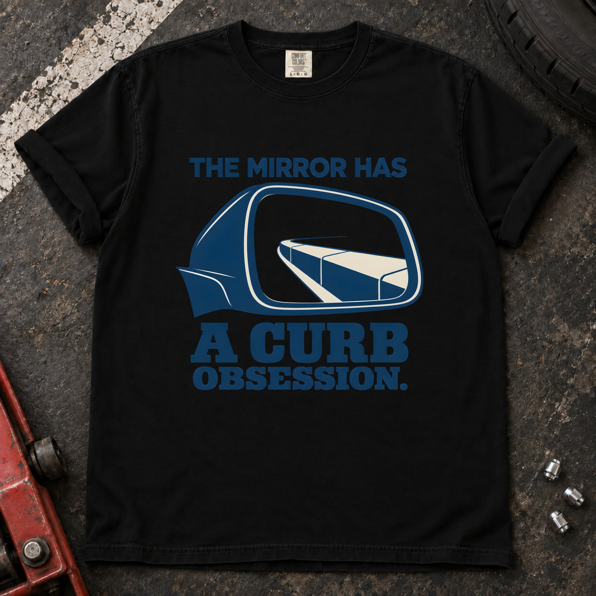 Black T-shirt showing a side mirror reflecting a curb with 'The mirror has a curb obsession'.
