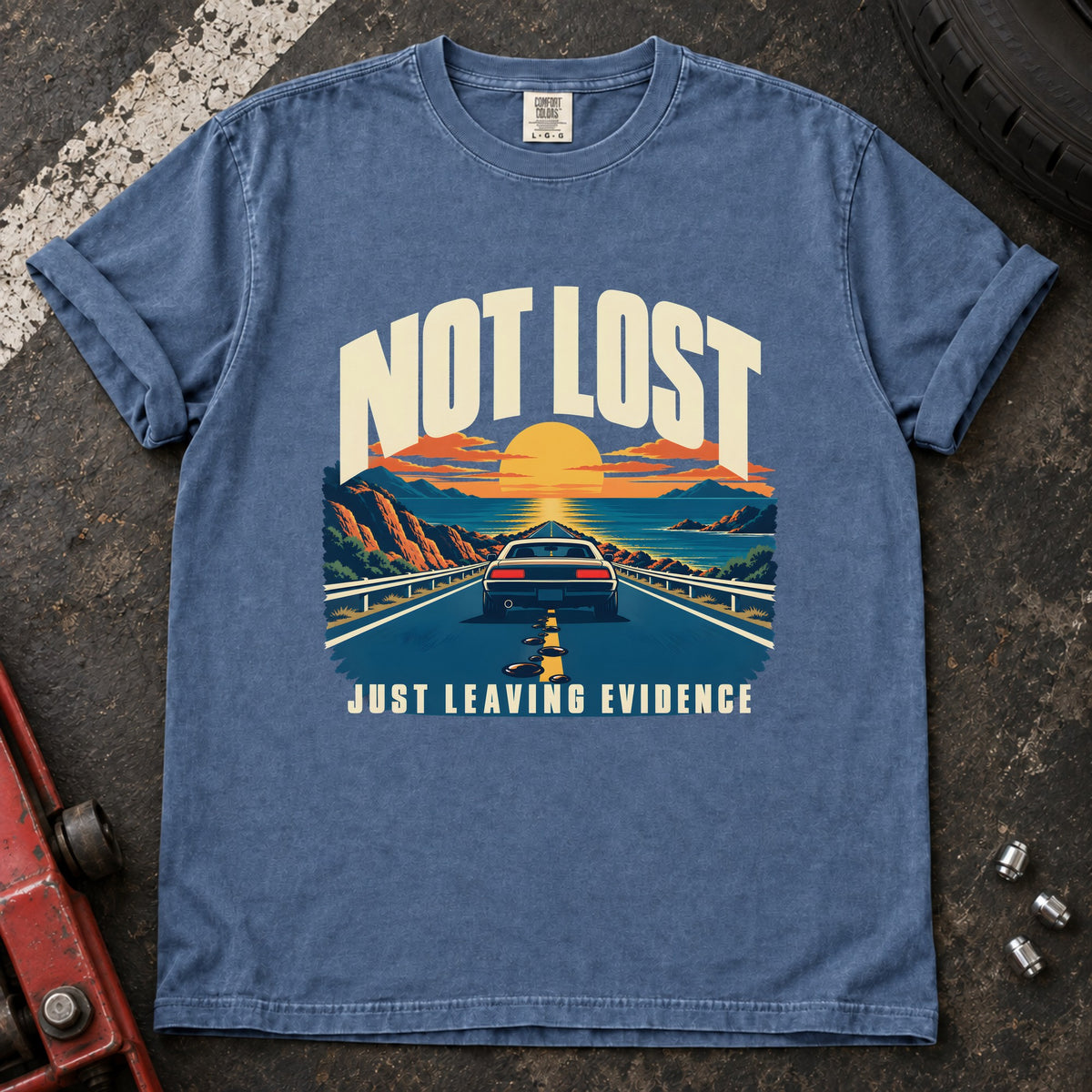 Blue Jean T-shirt showing a car on a sunset road with 'Not lost. Just leaving evidence'.