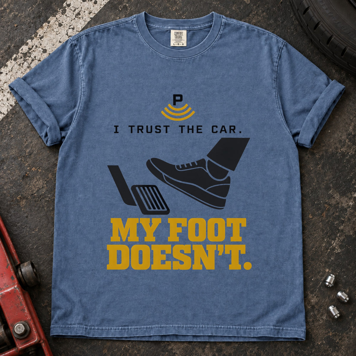 Blue Jean T-shirt showing a shoe near a pedal and a parking-assist symbol with 'I trust the car. My foot doesn't'.