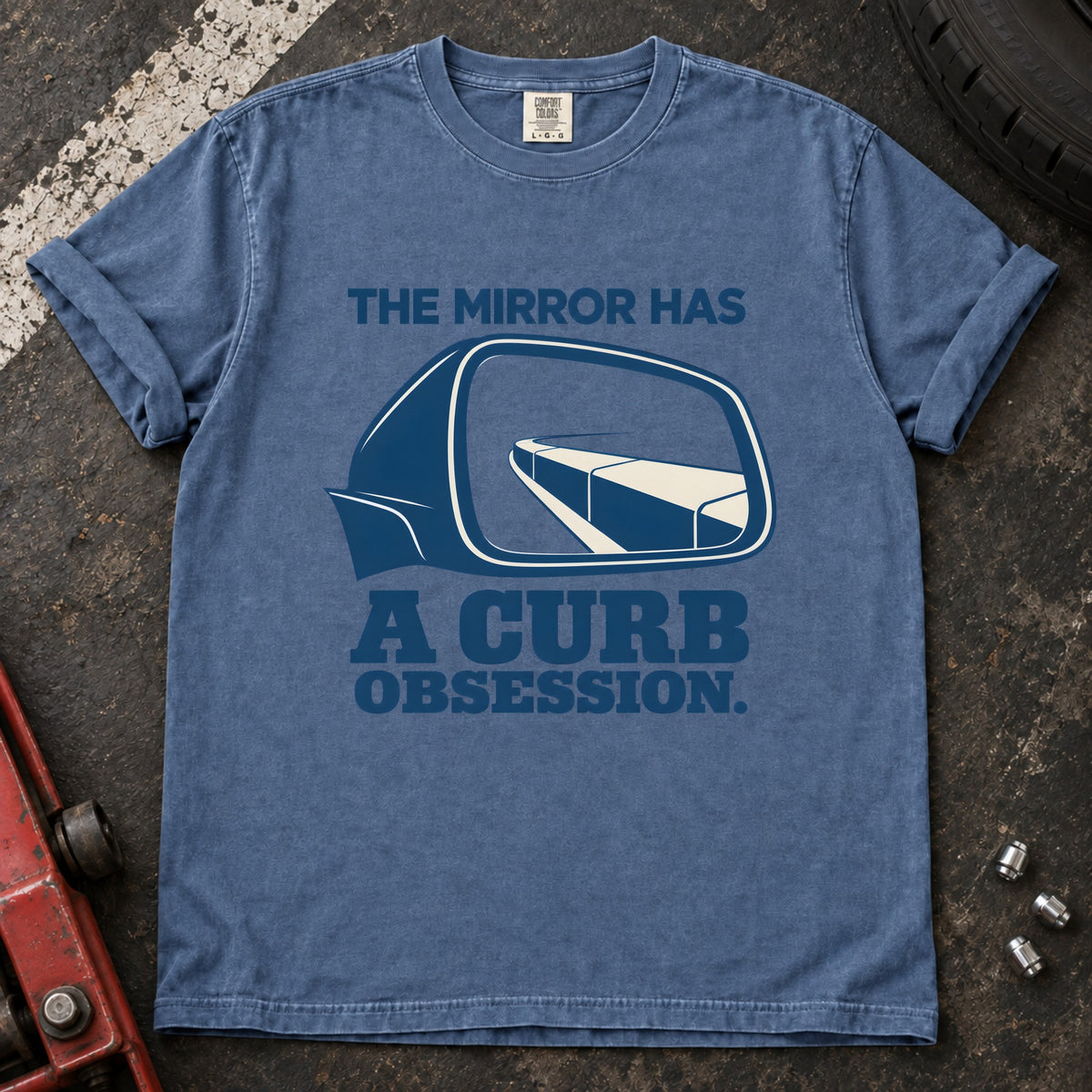 Blue Jean T-shirt showing a side mirror reflecting a curb with 'The mirror has a curb obsession'.