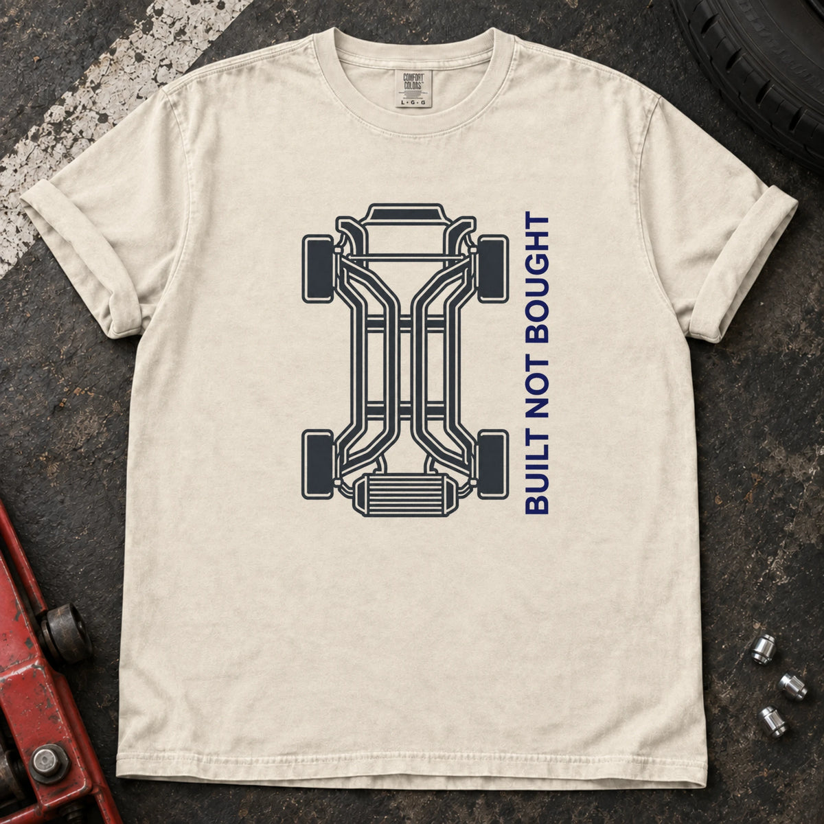Ivory car enthusiast T-shirt. A chassis outline celebrates built, not bought.