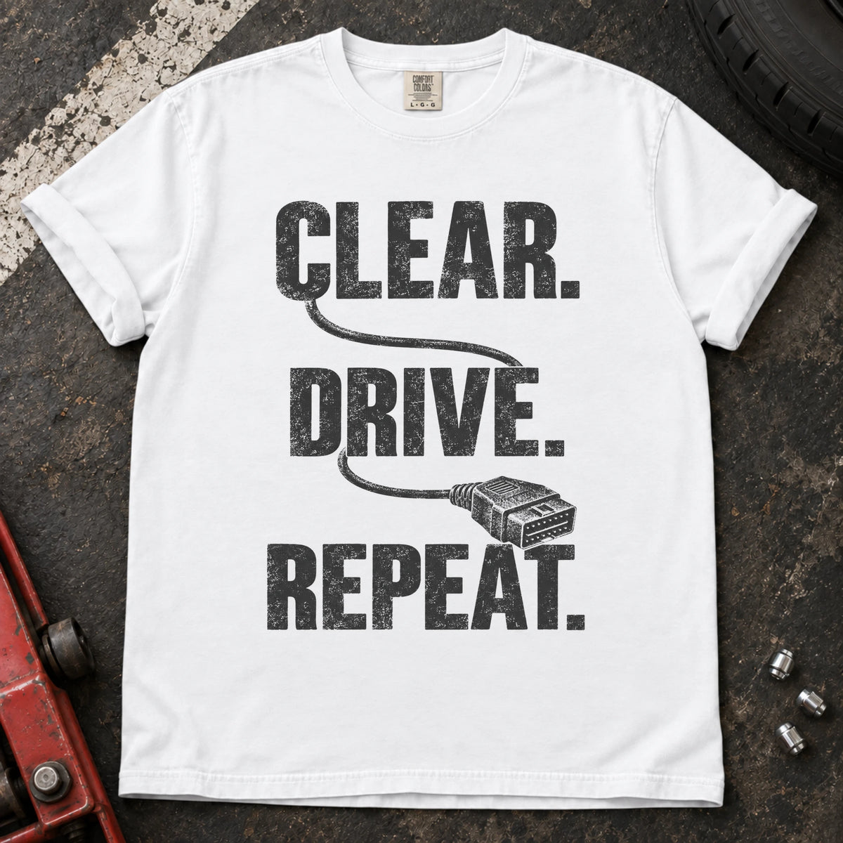 White car enthusiast T-shirt. A diagnostic cable connects clear, drive, repeat.