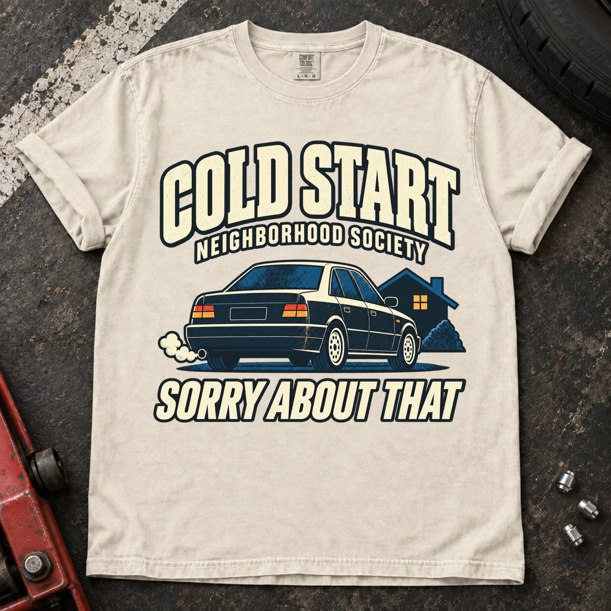 Ivory car enthusiast T-shirt. A car outside a house apologizes for the Cold Start Neighborhood Society.