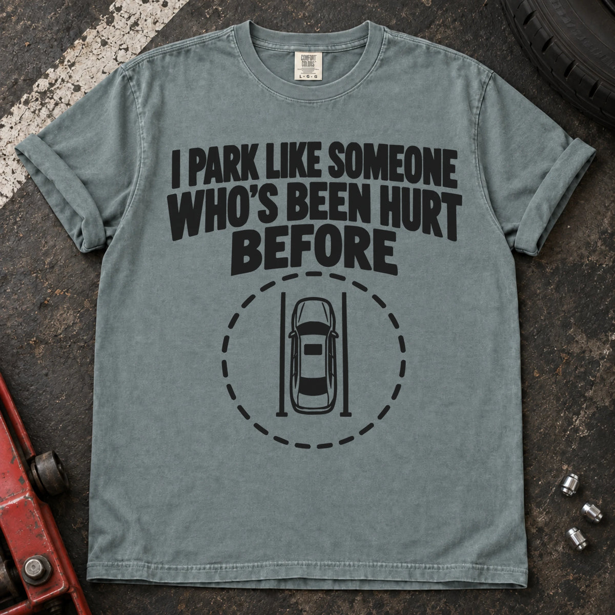 Bay T-shirt showing an overhead car inside a dashed circle with 'I park like someone who's been hurt before'.