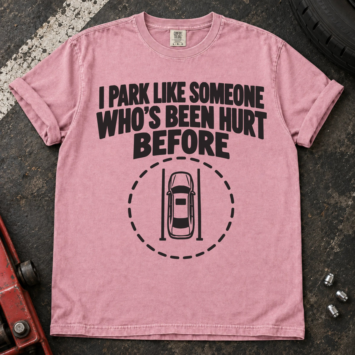 Blossom T-shirt showing an overhead car inside a dashed circle with 'I park like someone who's been hurt before'.