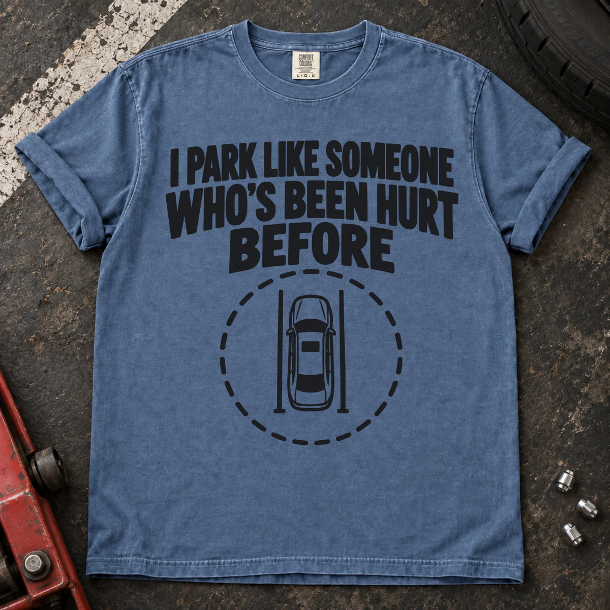 Blue Jean T-shirt showing an overhead car inside a dashed circle with 'I park like someone who's been hurt before'.