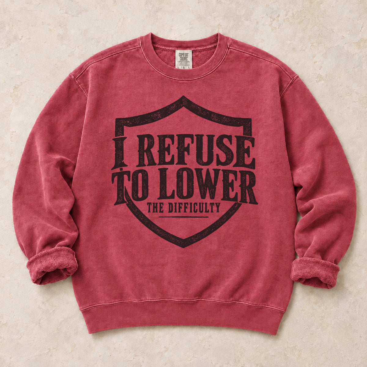 Crimson gaming sweatshirt. A shield frames the refusal to lower the difficulty.