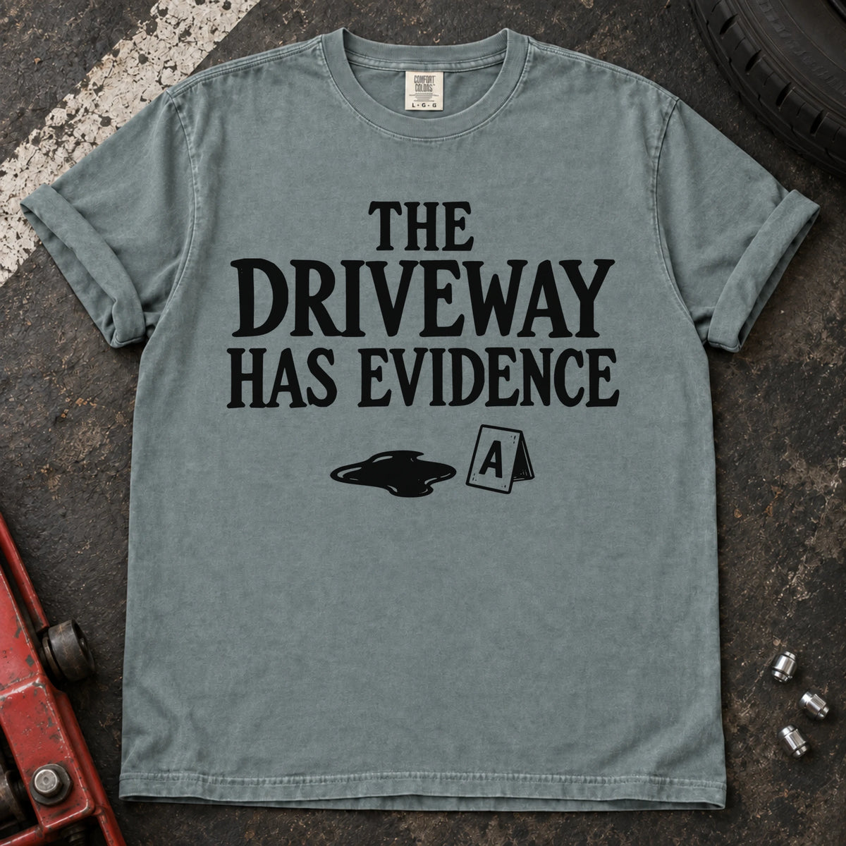 Bay T-shirt showing an oil puddle and evidence marker beneath 'The driveway has evidence'.