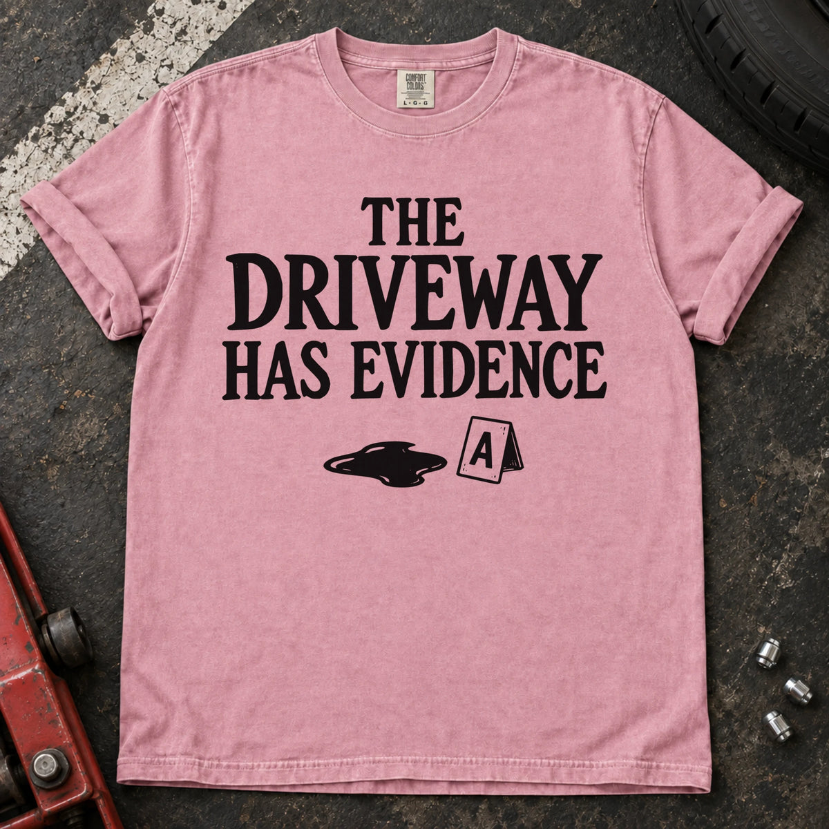 Blossom T-shirt showing an oil puddle and evidence marker beneath 'The driveway has evidence'.