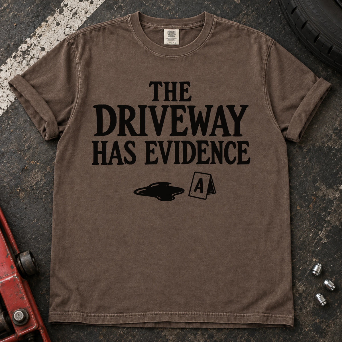 Espresso T-shirt showing an oil puddle and evidence marker beneath 'The driveway has evidence'.