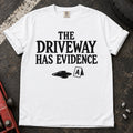 White T-shirt showing an oil puddle and evidence marker beneath 'The driveway has evidence'.