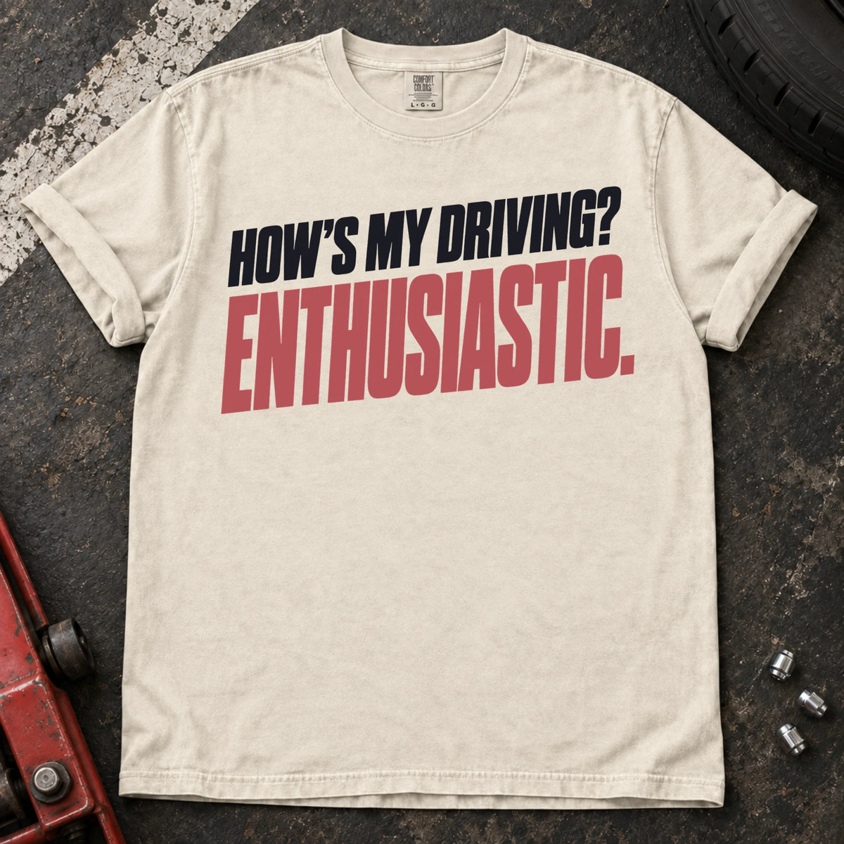 Ivory car enthusiast T-shirt. How's my driving? Enthusiastic. Bold lettering for the self-aware car lover.