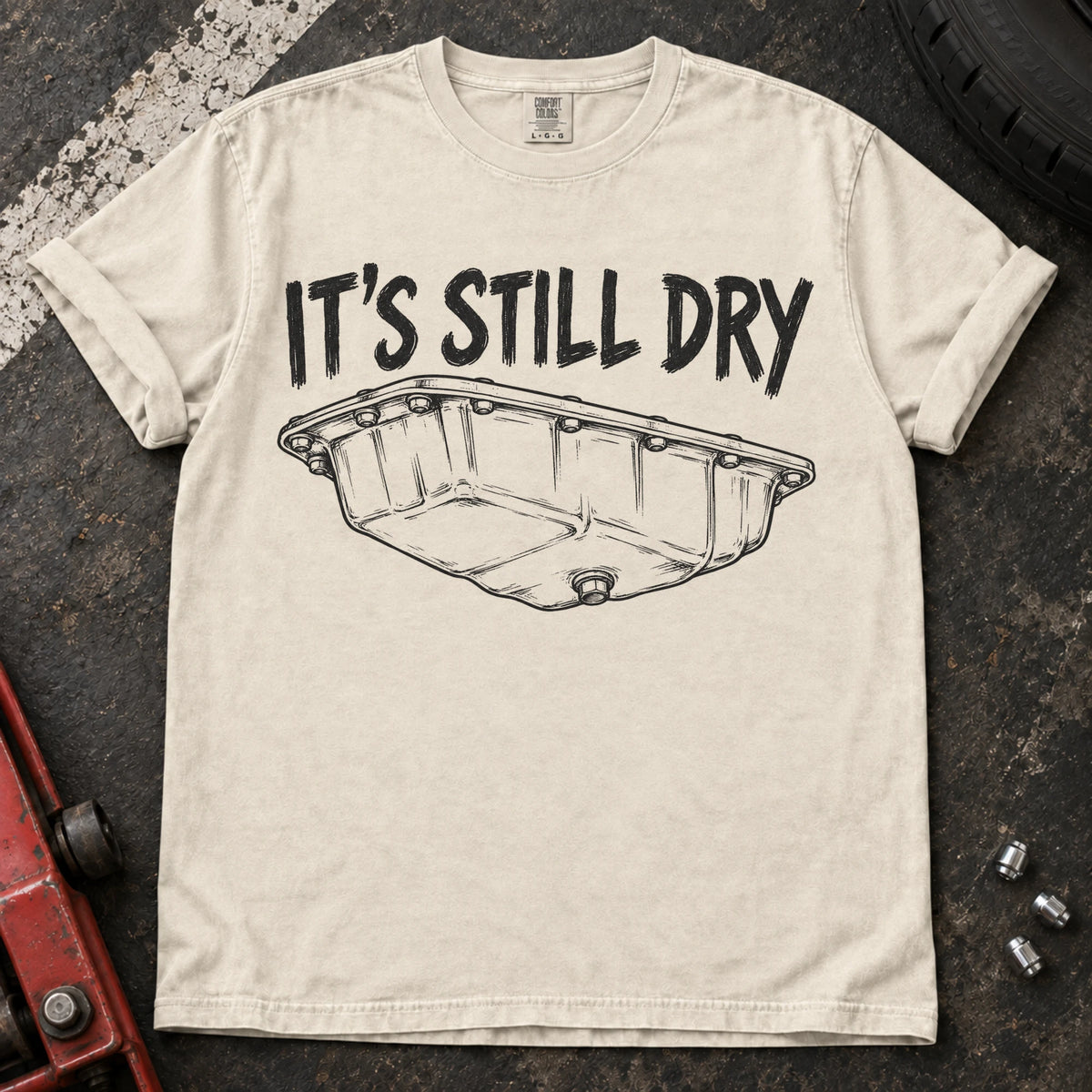 Ivory car enthusiast T-shirt. An oil-pan illustration makes it's still dry a cautious automotive joke.