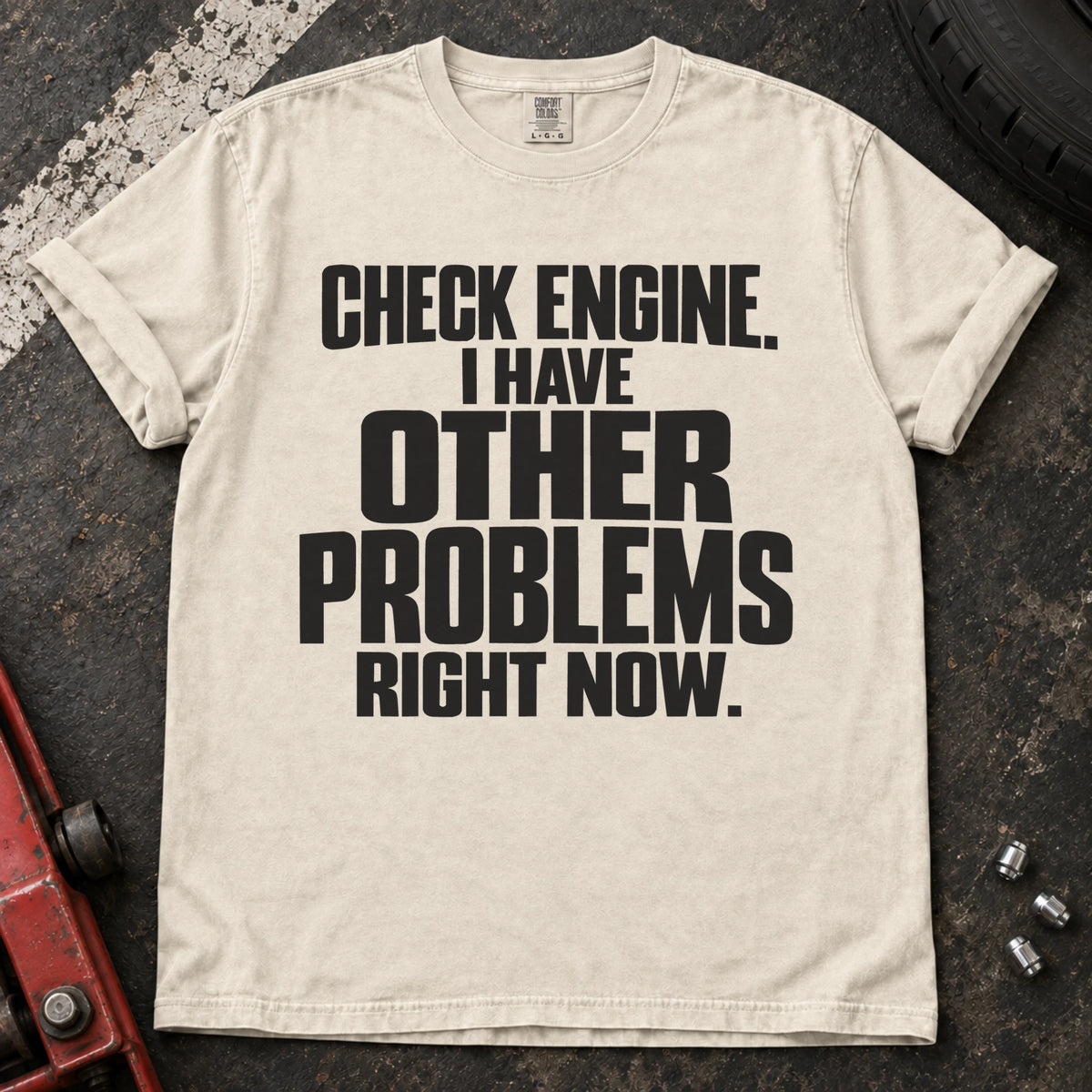 Ivory T-shirt reading 'Check engine. I have other problems right now' in stacked lettering.