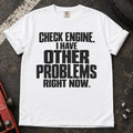 White T-shirt reading 'Check engine. I have other problems right now' in stacked lettering.