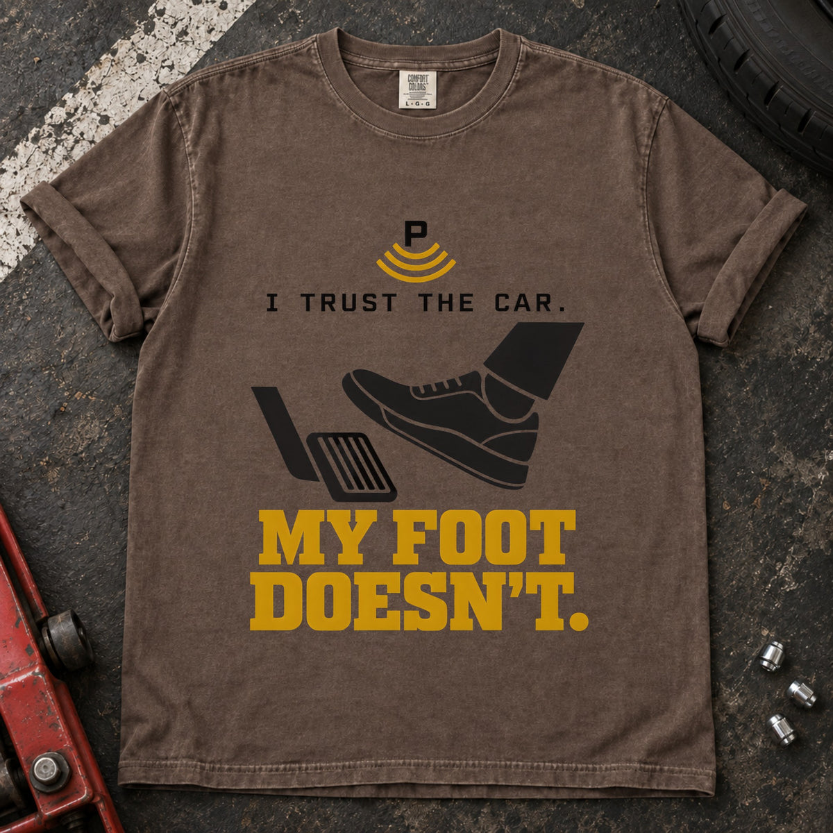 Espresso T-shirt showing a shoe near a pedal and a parking-assist symbol with 'I trust the car. My foot doesn't'.