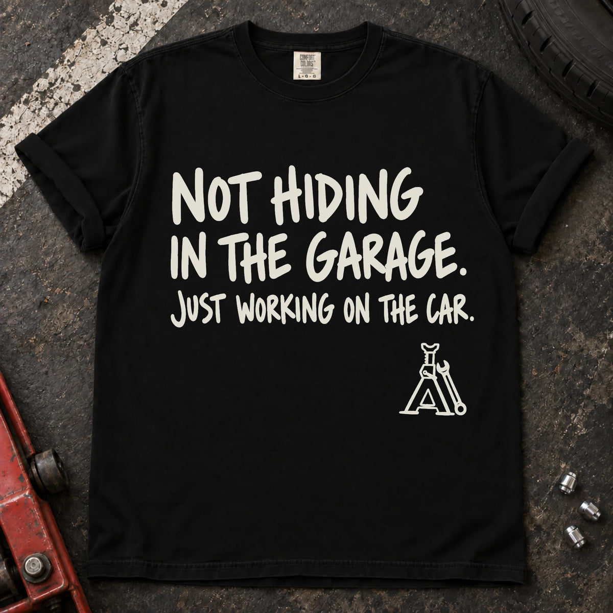 Black car enthusiast T-shirt. A jack stand backs not hiding in the garage, just working on the car.