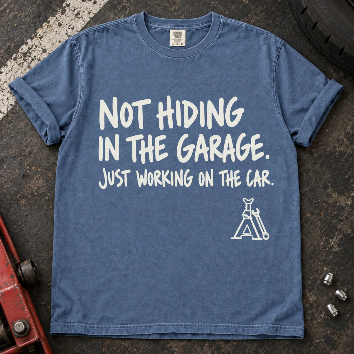 Blue Jean car enthusiast T-shirt. A jack stand backs not hiding in the garage, just working on the car.