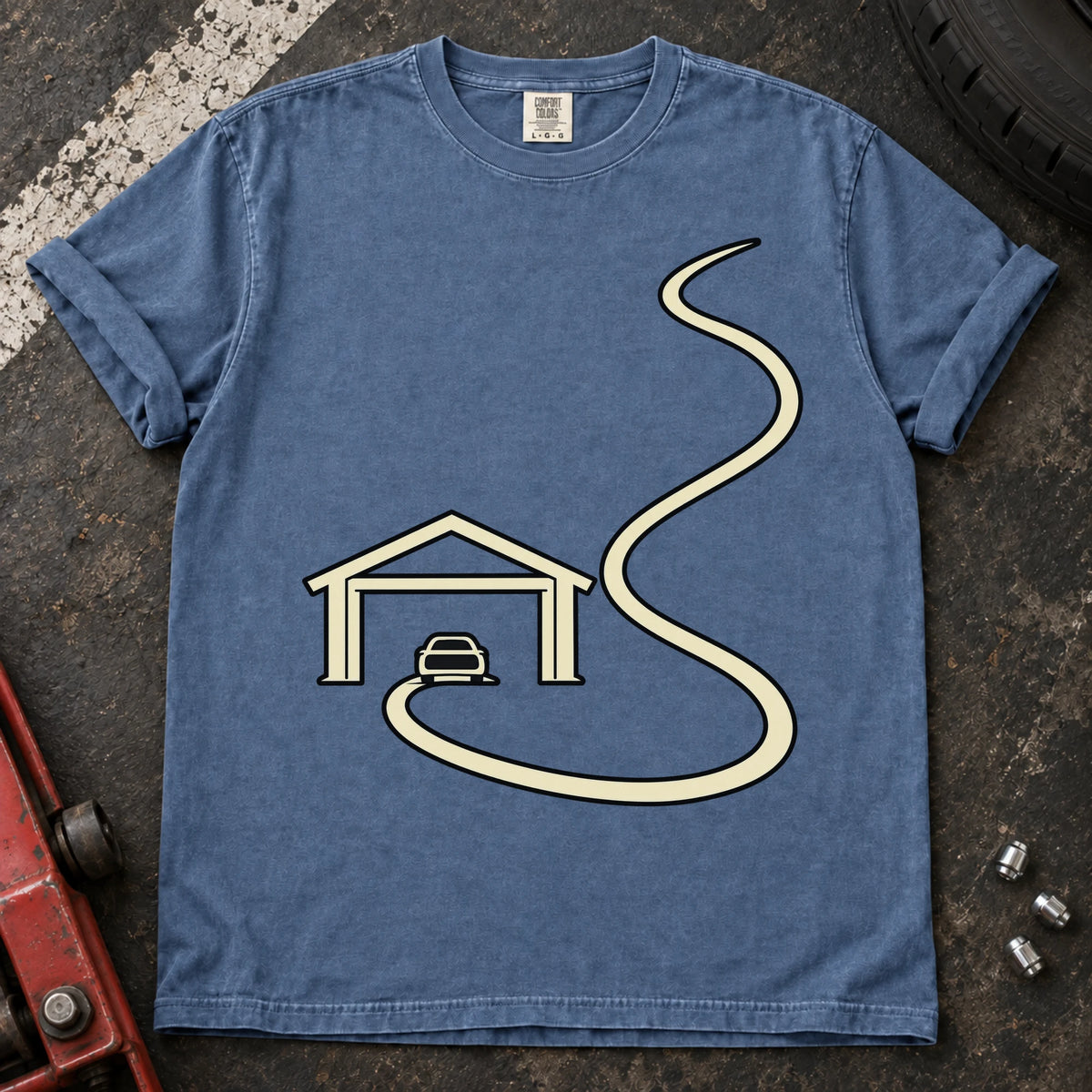 Blue Jean car enthusiast T-shirt. A minimal garage opens onto a long winding road.