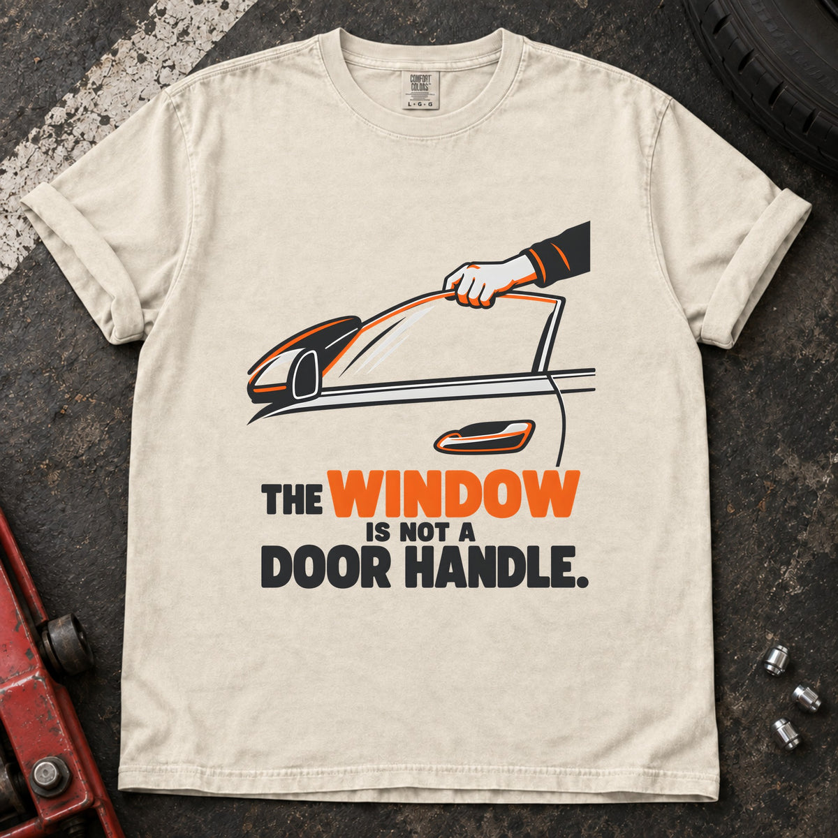 Ivory T-shirt showing a hand reaching through a car window with 'The window is not a door handle'.