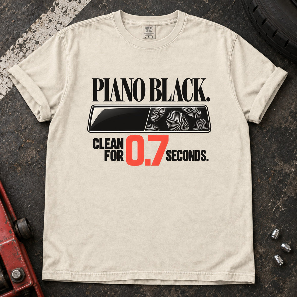 Ivory T-shirt showing fingerprints on a trim panel with 'Piano black. Clean for 0.7 seconds'.