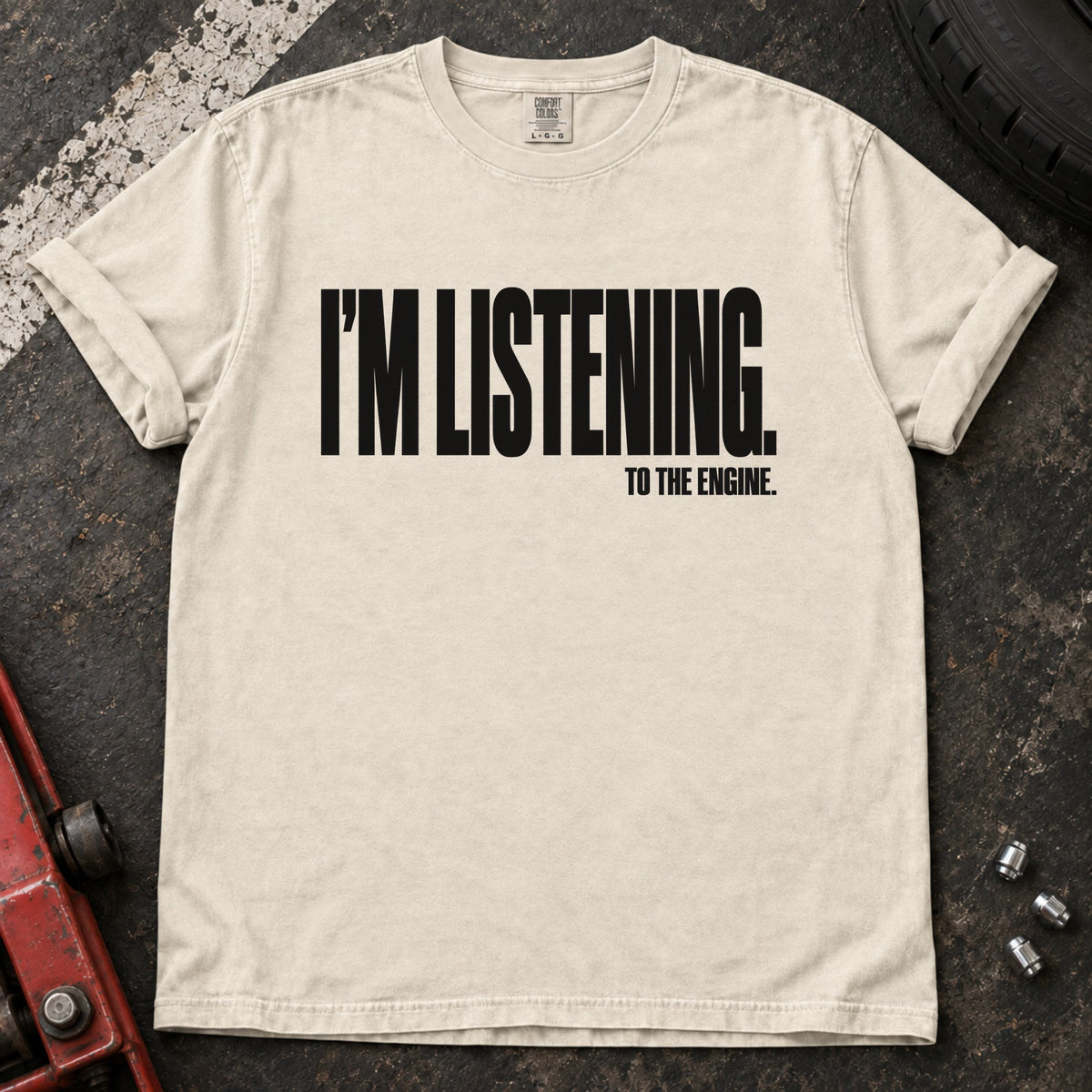 Ivory T-shirt with bold condensed lettering reading 'I'm listening to the engine'.