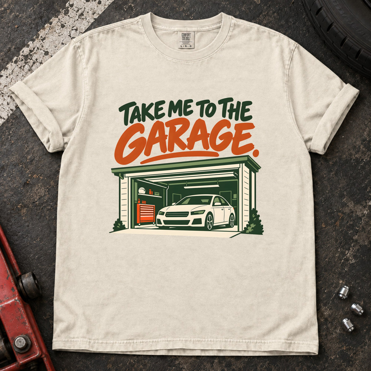 Ivory T-shirt showing a car inside a garage beneath green and orange 'Take me to the garage' lettering.