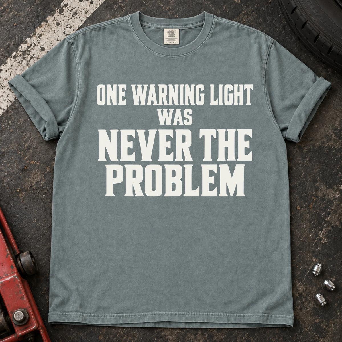 Bay T-shirt with serif lettering reading 'One warning light was never the problem'.