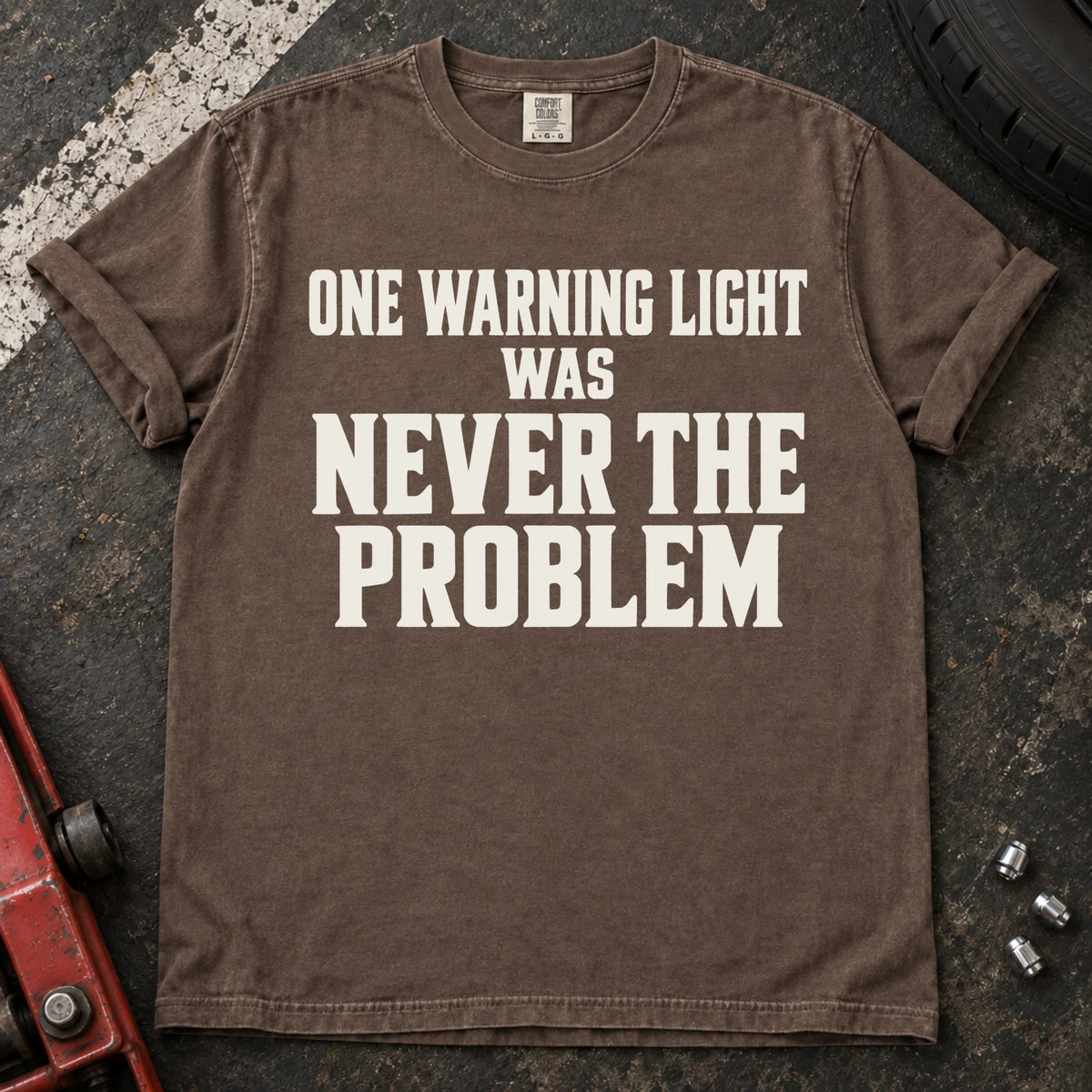 Espresso T-shirt with serif lettering reading 'One warning light was never the problem'.