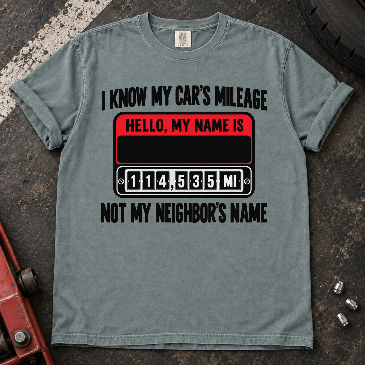 Bay T-shirt showing a name badge and odometer with 'I know my car's mileage, not my neighbor's name'.