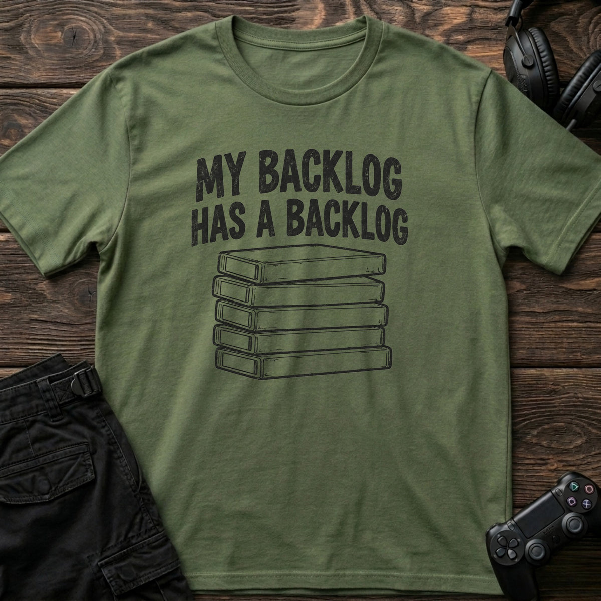 Military Green gaming T-shirt. A stack of game cases illustrates my backlog has a backlog.
