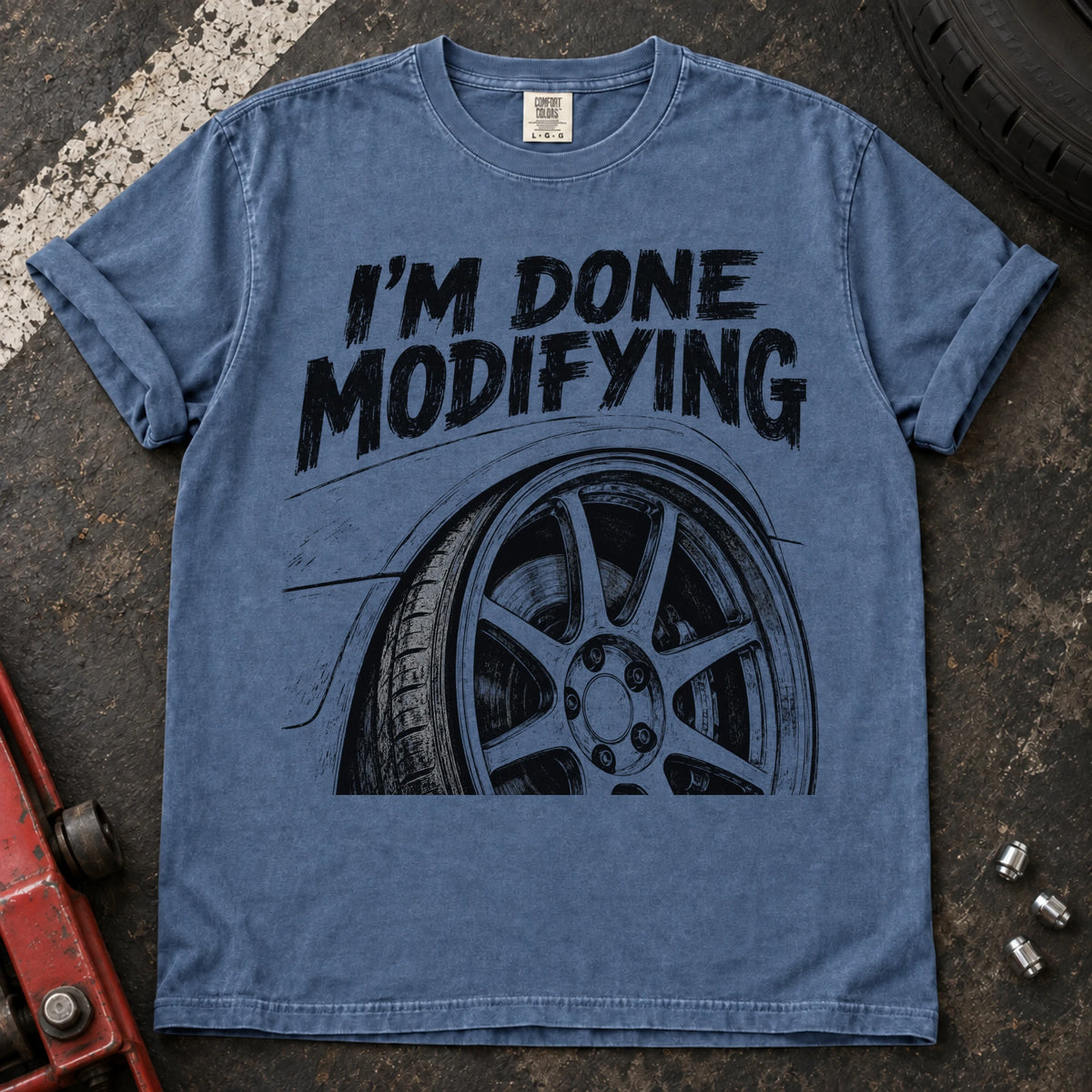 Blue Jean car enthusiast T-shirt. A modified wheel sits under the familiar promise, I'm done modifying.