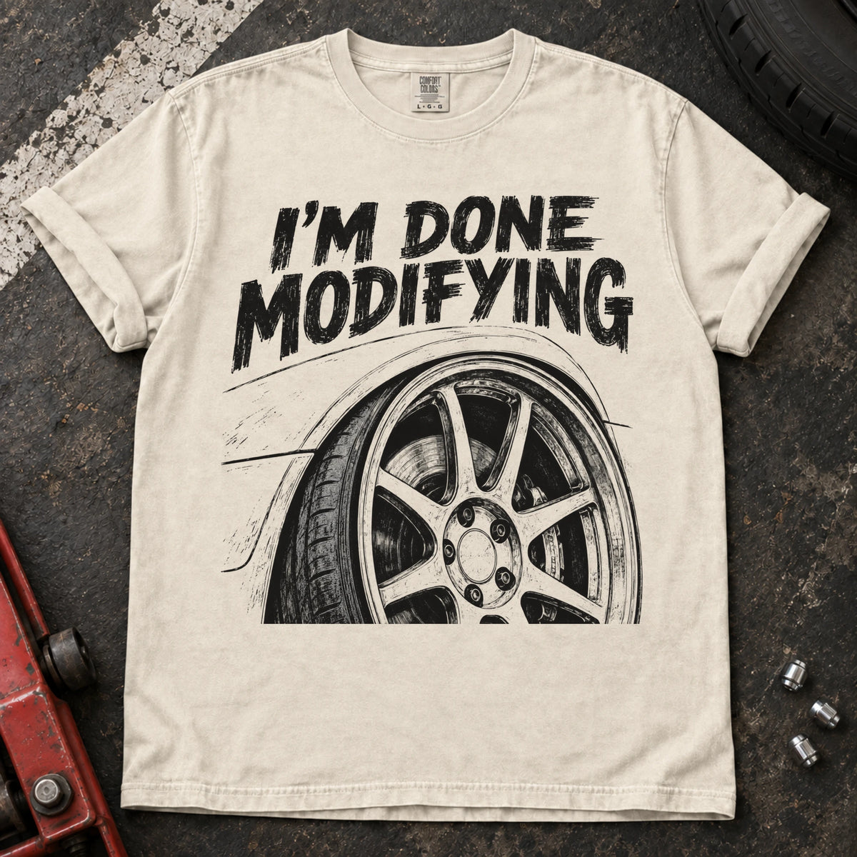 Ivory car enthusiast T-shirt. A modified wheel sits under the familiar promise, I'm done modifying.