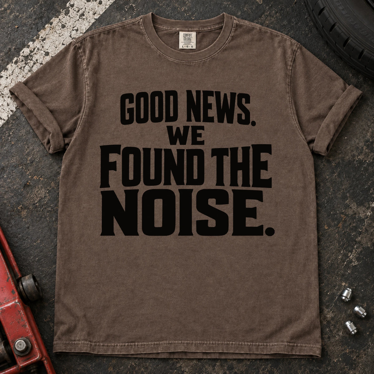 Espresso T-shirt with bold stacked lettering reading 'Good news. We found the noise'.