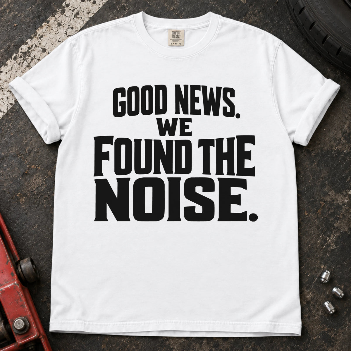 White T-shirt with bold stacked lettering reading 'Good news. We found the noise'.