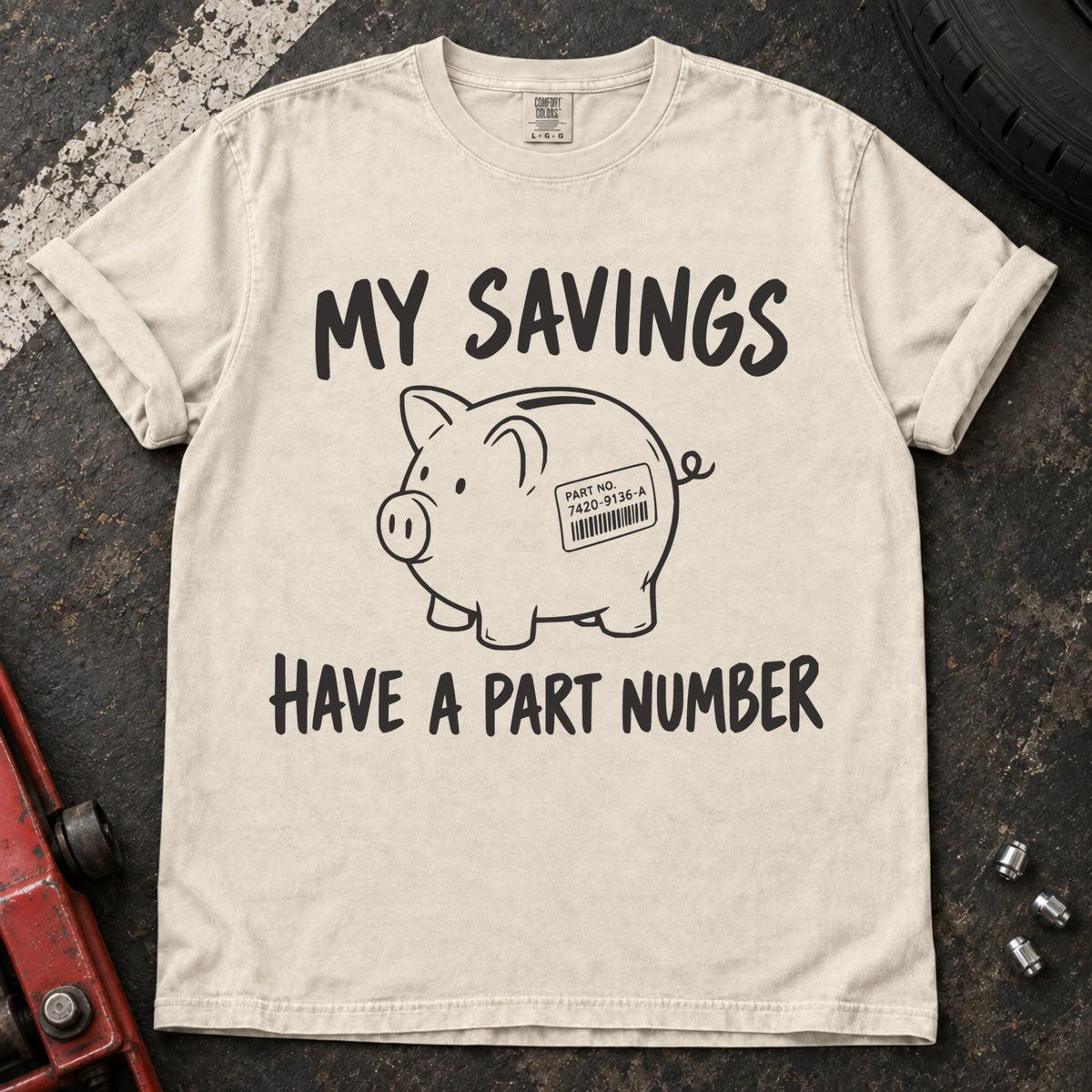 Ivory T-shirt showing a piggy bank with a parts label beneath 'My savings have a part number'.