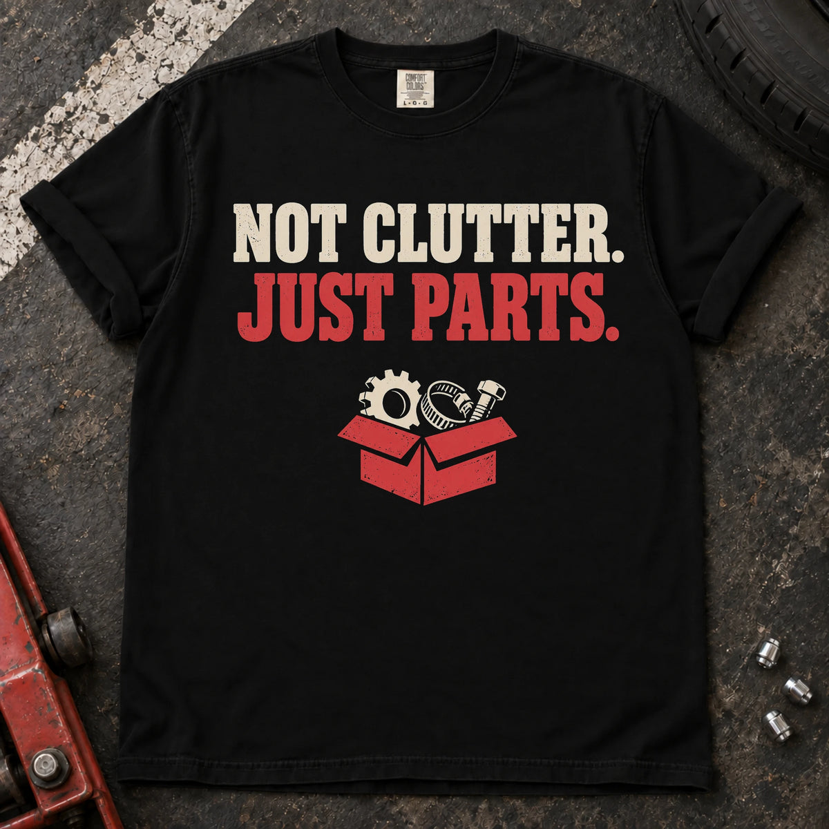Black car enthusiast T-shirt. A box of components insists not clutter, just parts.