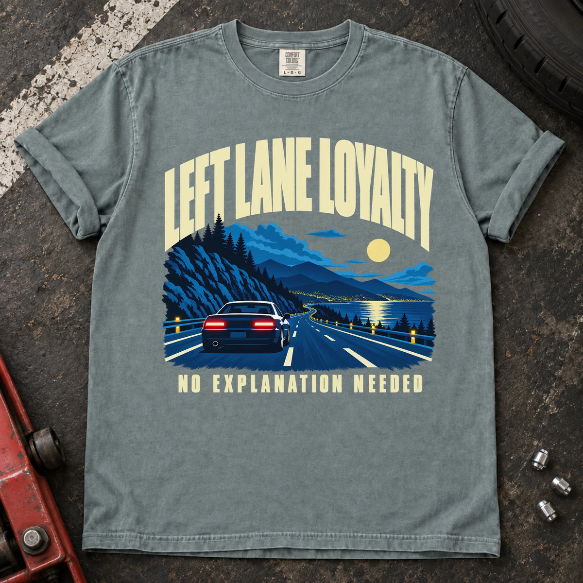 Bay T-shirt showing a car on a moonlit mountain road with 'Left lane loyalty. No explanation needed'.