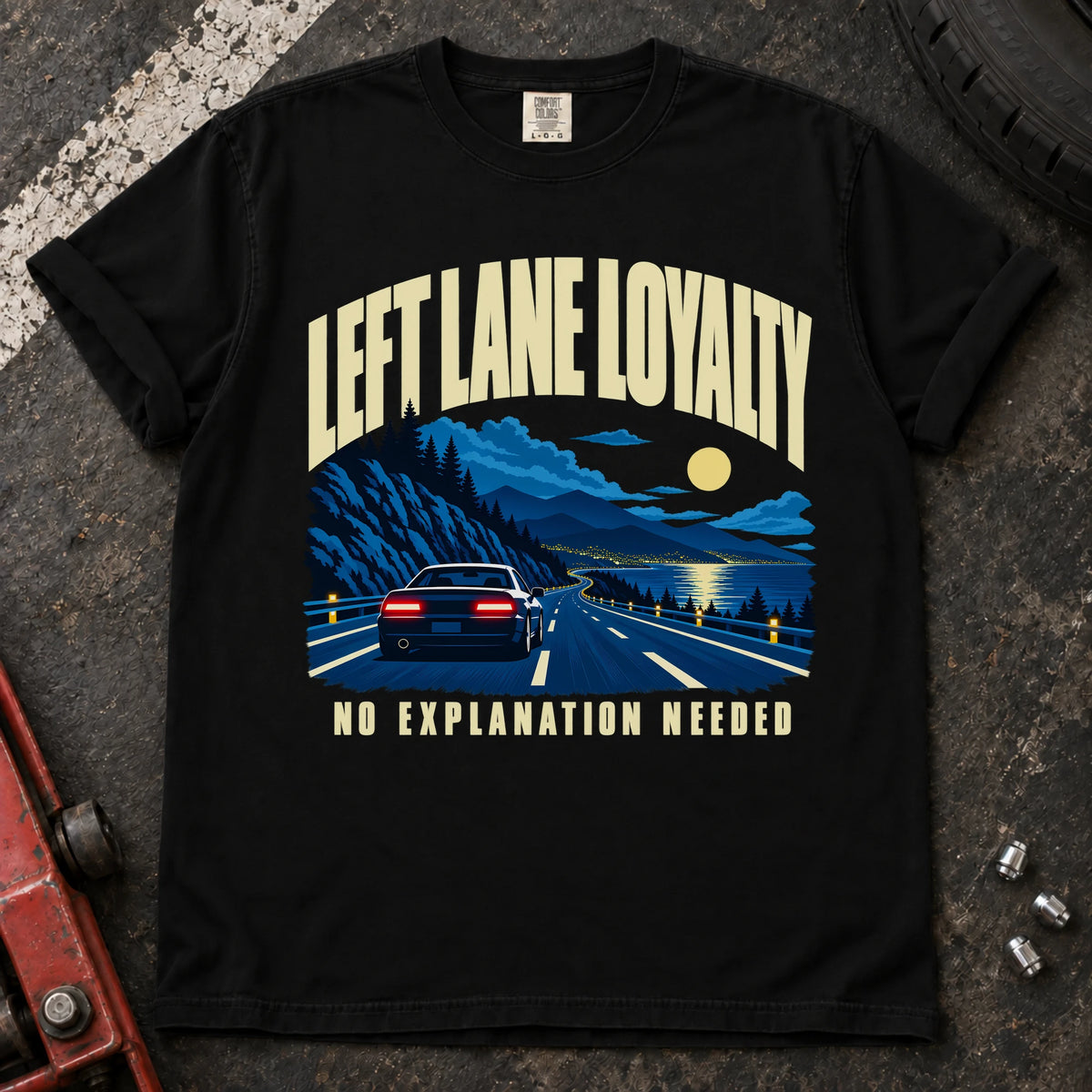 Black T-shirt showing a car on a moonlit mountain road with 'Left lane loyalty. No explanation needed'.