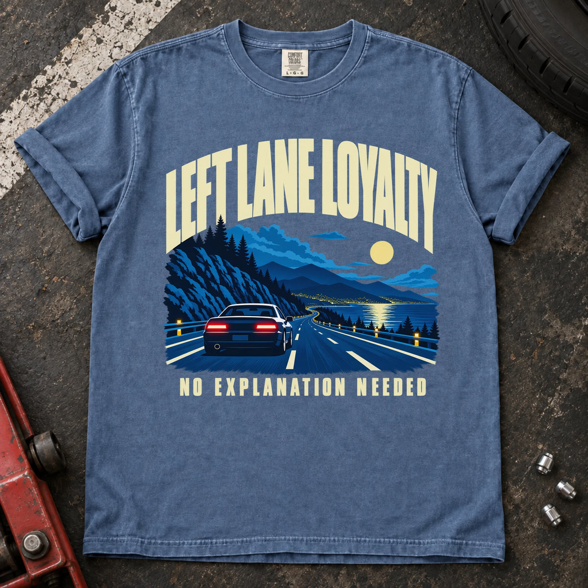 Blue Jean T-shirt showing a car on a moonlit mountain road with 'Left lane loyalty. No explanation needed'.