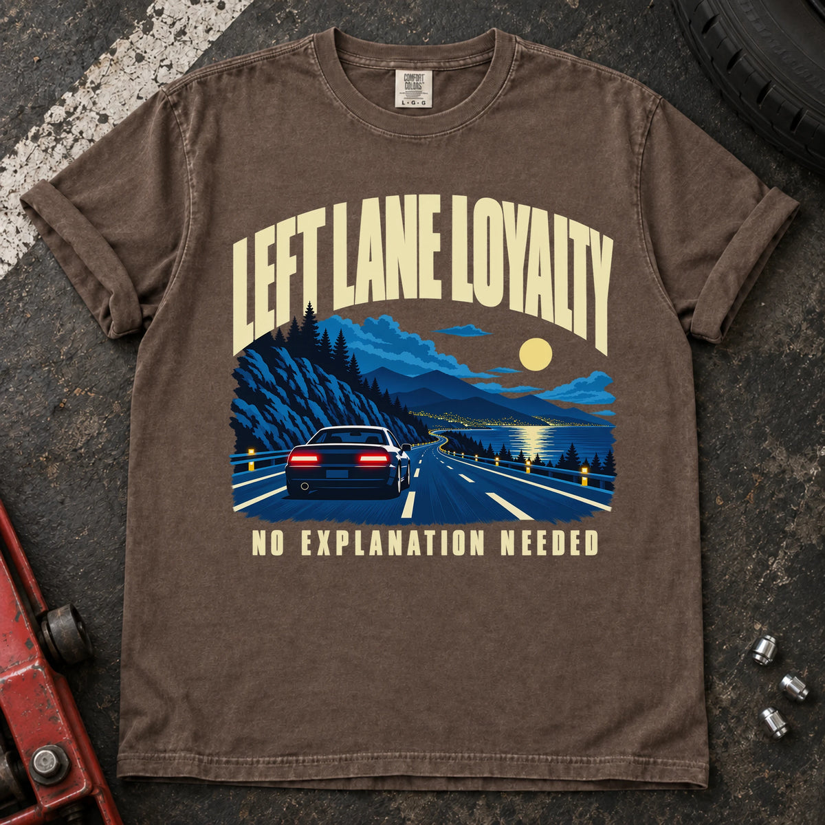 Espresso T-shirt showing a car on a moonlit mountain road with 'Left lane loyalty. No explanation needed'.