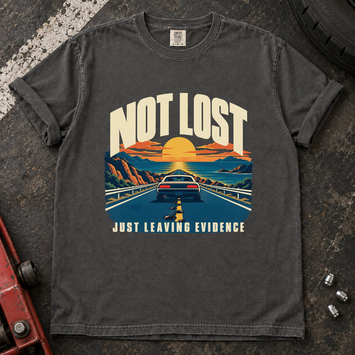 Pepper T-shirt showing a car on a sunset road with 'Not lost. Just leaving evidence'.