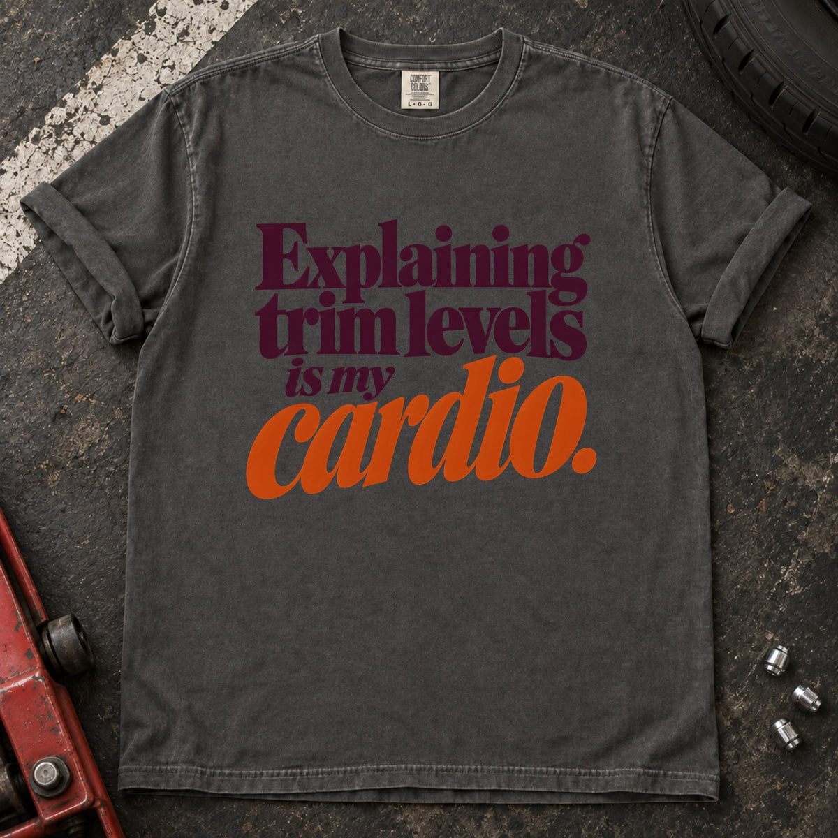 Pepper T-shirt with burgundy and orange lettering reading 'Explaining trim levels is my cardio'.