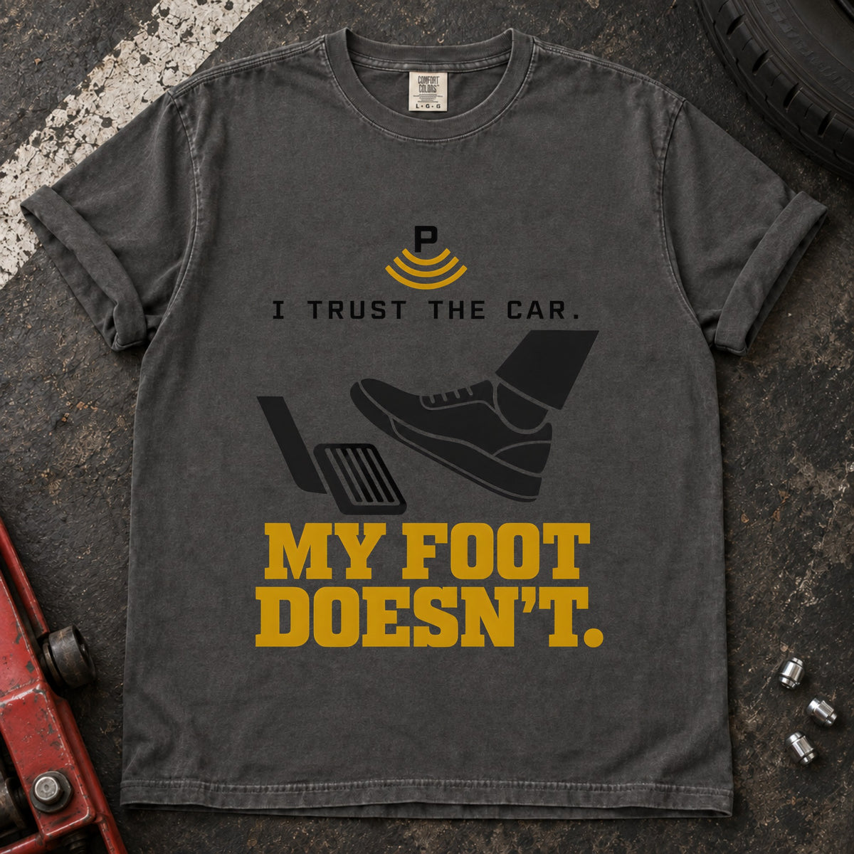 Pepper T-shirt showing a shoe near a pedal and a parking-assist symbol with 'I trust the car. My foot doesn't'.